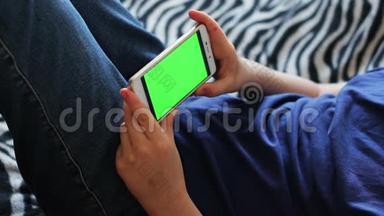 手持触摸屏设备，使用智能手机特写青少年手。 彩色钥匙，绿色屏幕
